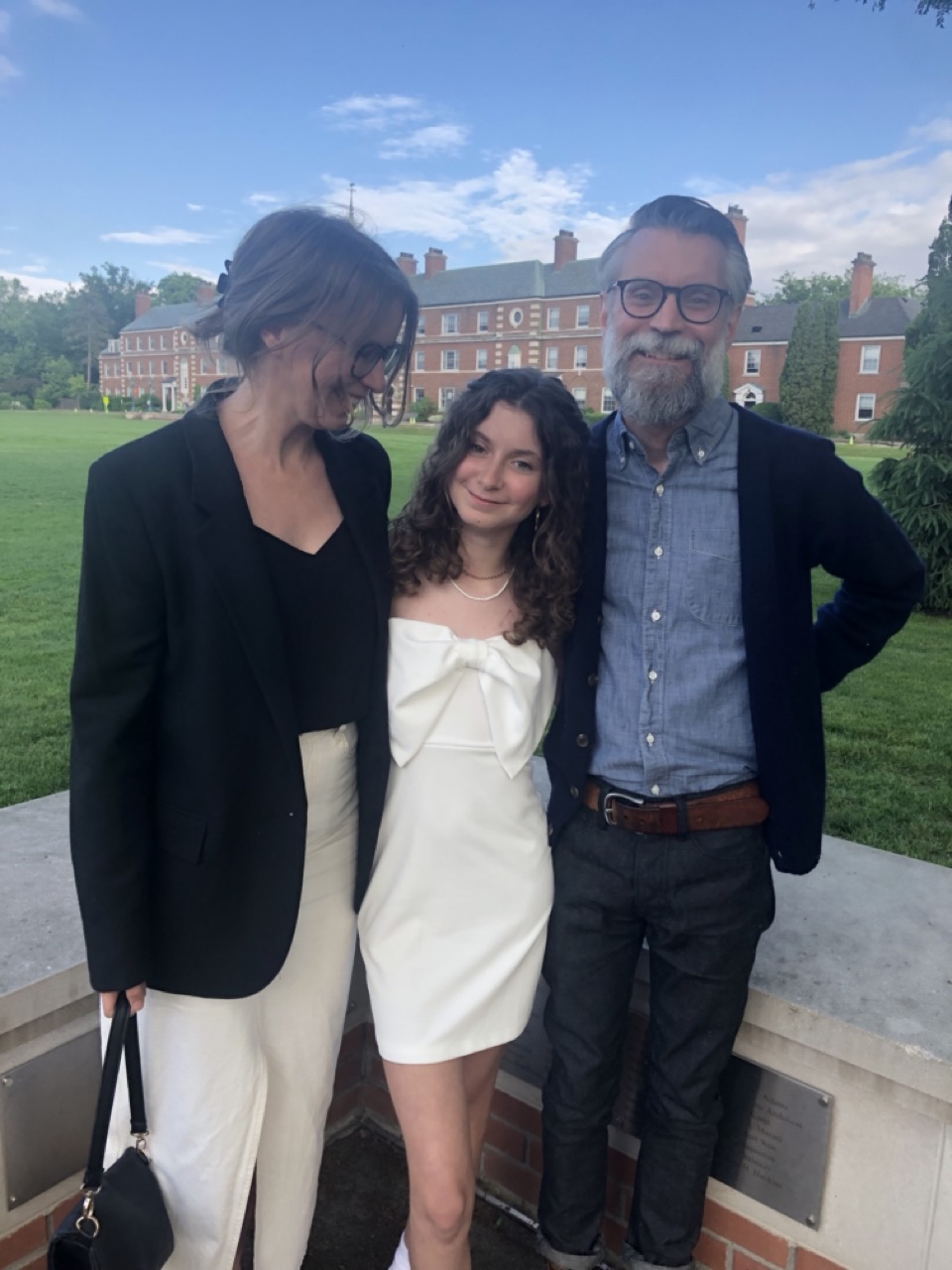 Cole is standing with her daughter and husband, they are dressed elegantly and celebrating her daughter's eighth grade graduation 